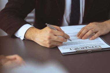 İş adamı sözleşme kağıtlarını ya da iş hukukunu güven ve profesyonellikle imzalar. Resmi iş anlaşması için şirket toplantısında el ele tutuşmak. Eşitlik