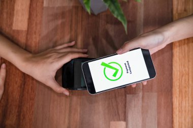 QR kodu parasız ödeme taraması için ekranda gösterilir. Kapalı eller, mobil uygulamadan elektronik işlem yoluyla para aktarmak için akıllı telefonu tutuyor. Hızlı ödeme için barkod teknolojisi. Coşkulu.