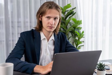 Siyah takım elbiseli bir iş adamı çalışma masasında dizüstü bilgisayarla çalışıyor. Akıllı yönetici finansal verileri araştırıyor ve modern işyerindeki kurumsal dizüstü bilgisayarlarda pazarlama stratejisi planlıyor. Varlık