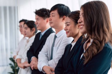 Cohesive group of businesspeople standing in row, holding hand in line together after meeting to promote harmony in workplace. Asian office workers strong teamwork and unity concept.