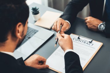 İş anlaşması yapılırken iki işadamı masanın karşısında oturuyor. Şirket avukatı, sözleşmeyi imzalaması için müvekkiline ya da ortağına kalem veriyor ve anlaşmayı imzayla imzalıyor. Coşkulu