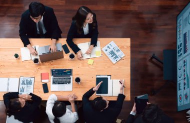Top view manager or office worker give presentation in harmony conference room to business colleague, BI data dashboard on screen and pile of financial analyzed data reports on meeting table.
