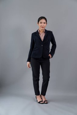 Kendine güvenen genç iş kadınının tüm vücut boyu resmi izole bir arka planda duruyor, resmi siyah takım elbise içinde poz veriyor. Ofisteki kadın ya da yönetici, zeki ve profesyonel görünümlü. Coşkulu.