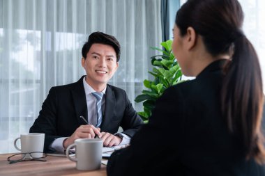 İki Asyalı ofis çalışanı şirket işyerinde birlikte çalışıp tartışıyorlar. Gülümseyen ve planlayan iş arkadaşları, kurumsal çalışma alanındaki dostane çalışma ortamında çalışırlar. Sevinçli.