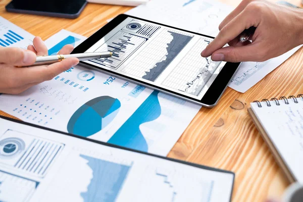 Ofisteki analist ekibi, iş performansını artırmak için tablet ekranında grafik ve grafik olan BI panelini kullanarak çalışma alanındaki pazarlama stratejisi için finansal veri analizi yapmakla meşgul. Varlık
