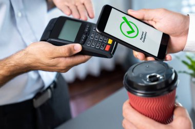 NFC QR kod cihazı ile el ele tutuşan akıllı telefon, hızlı dijital işlemler için temas kurulamayan ödeme kodlarını tarıyor. Modern yaşam tarzı ödeme teknolojisi için cep telefonundaki online bankacılık uygulaması. coşkulu