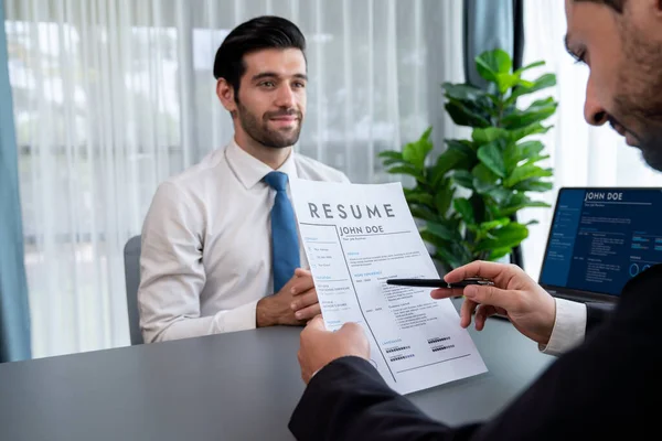 Interviewing job applicant in office with resume paper. Candidate wear suit for formal conversation with interviewer. Recruitment process with question about career and work experience. Fervent