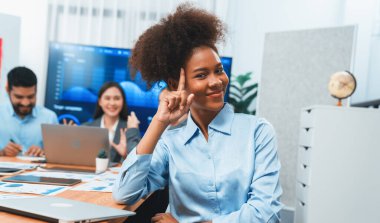 Bir grup ofis çalışanı ile birlikte arka planda ekranda gösterim paneliyle buluşan mutlu Afrikalı genç bir iş kadını portresi. Takım toplantısında kendine güveni tam bir ofis hanımı. Uyum
