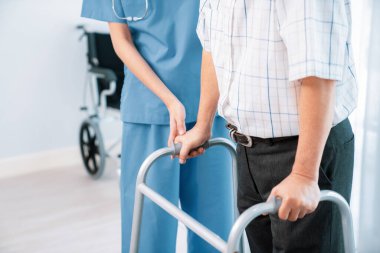 Physiotherapist assists her contented senior patient on folding walker. Recuperation for elderly, seniors care, nursing home.