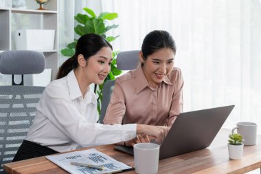 Modern ofis çalışma alanında iş birliği yapan iki genç ofis çalışanı, modern ofis çalışanı olarak profesyonelliklerini sergileyerek, dizüstü bilgisayarda tartışıyorlar ve birlikte çalışıyorlar. Coşkulu.