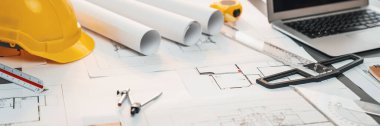 Mimari mimari tasarım, güvenlik kaskı veya başlığı takılı mühendislik çalışma alanı masası üzerine müteahhit proje belgeleriyle tasarım için tasarım planı ve mühendislik aracı tasarladı. İçgörü