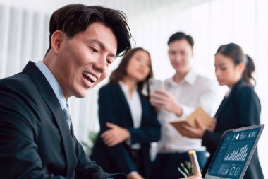 Portrait of focus young successful confident male manager, executive wearing business wear in harmony office arm crossed with blurred meeting background of colleagues, office worker.