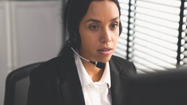 Competent female operator working on computer and talking with clients. Concept relevant to both call centers and customer service offices.