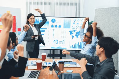 İş adamları TV ekranında başarılı bir sunum veya veri analizi toplantısından sonra kutlama yapıyorlar. Mutlu takım ofis odasında toplanıyor, kutlama jestleriyle işbirliği için tezahürat yapıyorlar. Uyum