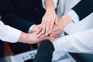 Top view closeup business team of suit-clad businesspeople join hand stack together. Colleague collaborate and work together to promote harmony and teamwork concept in office workplace.
