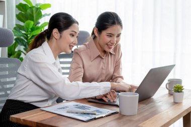 Modern ofis çalışma alanında iş birliği yapan iki genç ofis çalışanı, modern ofis çalışanı olarak profesyonelliklerini sergileyerek, dizüstü bilgisayarda tartışıyorlar ve birlikte çalışıyorlar. Coşkulu.