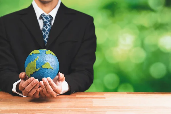 Businessman holds paper earth as symbol of eco environmental awareness for sustainable world using clean energy and zero CO2 emission. Eco-friendly corporate with go green policy to save earth. Alter