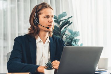 Erkek müşteri hizmetleri operatörü ya da telesales temsilcisi ofiste oturuyor, kulaklık takıyor ve müşteriyle satış desteği ya da kapanış konuşması yapıyor. Çağrı merkezi portresi. Varlık