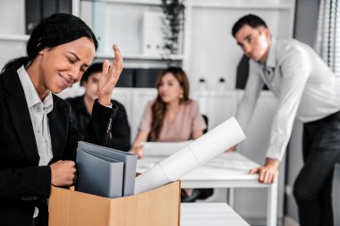 An emotional image of a fired employee packing up her possessions for not being competent. Feeling overwhelmed and embarrassed in front of her coworkers.