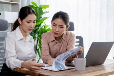 Modern ofis çalışma alanında iş birliği yapan iki genç ofis çalışanı, modern ofis çalışanı olarak profesyonelliklerini sergileyerek, dizüstü bilgisayarda tartışıyorlar ve birlikte çalışıyorlar. Coşkulu.