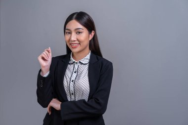 Tecrit edilmiş arka planda profesyonel kıyafetle poz veren kendine güvenen genç Asyalı iş kadını. Başarı sembolü, iyimserlik ve iş tanıtımları ve reklamlar için kurumsal ofis hanımı. Sevinçli.