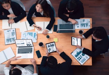 Top-view business team of financial data analysis meeting with business intelligence, report paper and dashboard on laptop for marketing strategy. Business people working together in office of harmony