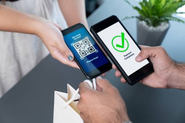 Parasız ödeme taraması için QR kodu ekranda görüntülendi. Kapalı eller, mobil uygulamadan elektronik işlem yoluyla para aktarmak için akıllı telefonu tutuyor. Hızlı ödeme için barkod teknolojisi. Coşkulu