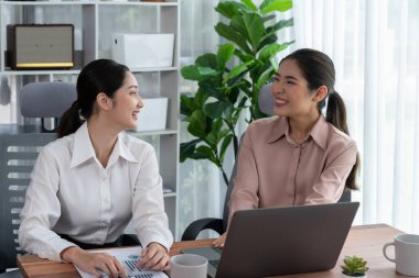 Modern ofis çalışma alanında iş birliği yapan iki genç ofis çalışanı, modern ofis çalışanı olarak profesyonelliklerini sergileyerek, dizüstü bilgisayarda tartışıyorlar ve birlikte çalışıyorlar. Coşkulu.