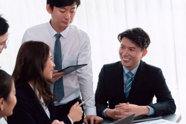 Harmony in office concept as business people analyzing dashboard paper together in workplace. Young colleagues give ideas at manager desk for discussion or strategy planning about project.