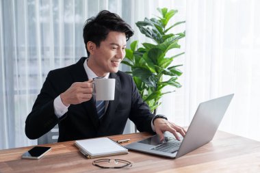 Ofis masasında dizüstü bilgisayarda çalışan bir iş adamı. Akıllı yönetici finansal iş verilerini araştırıyor ya da masada bilgisayarla stratejik iş pazarlaması planlıyor. Sevinçli.