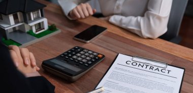 Temsilciyle ev kredisi sözleşmesini gözden geçiriyorum. Mali belgeleri ve vergi oranlarını, mülkiyet sahibi olmak için hesap makinesiyle analiz ediyorum. Yeni ev alımı ve finansman için anahtar imza. Coşkulu.