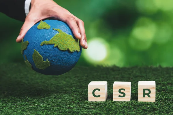 Businessman hand holding gesture with paper globe, CSR symbol cube. Eco-friendly green and ethical business company with no CO2 emission policy. Corporate social responsible for green community. Alter