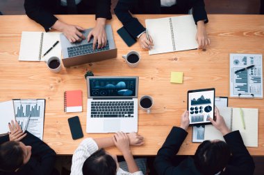 Top view manager or office worker give presentation in harmony conference room to business colleague, BI data dashboard on screen and pile of financial analyzed data reports on meeting table.