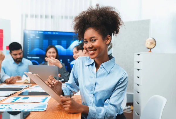 stock image Portrait of happy young african businesswoman with group of office worker on meeting with screen display business dashboard in background. Confident office lady at team meeting. Concord