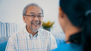 A young female doctor inquires about personal information of a contented senior at home. Medical care for the elderly, elderly illness, and nursing homes, home care.