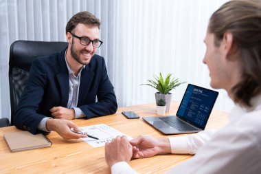 İş görüşmesinde iş adayı mülakatçıyla sohbet ediyor. İş başvurusunda bulunan kişi iş deneyimi ve özgeçmişinin dijital olarak dizüstü bilgisayar ve CV kağıtlarını İK yöneticisine sunar. Varlık