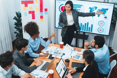 Modern toplantı odasındaki TV ekranında veri analizi paneliyle üst görünüm iş sunumu. İş adamlarının iş pazarlama stratejisini planlamak için beyin fırtınası yapması ya da birlikte çalışması. Uyum