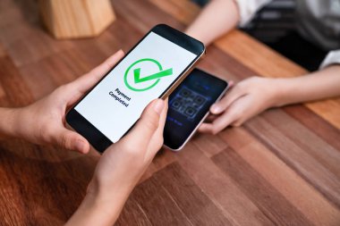 QR kodu parasız ödeme taraması için ekranda gösterilir. Kapalı eller, mobil uygulamadan elektronik işlem yoluyla para aktarmak için akıllı telefonu tutuyor. Hızlı ödeme için barkod teknolojisi. Coşkulu.