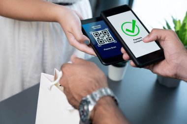 Parasız ödeme taraması için QR kodu ekranda görüntülendi. Kapalı eller, mobil uygulamadan elektronik işlem yoluyla para aktarmak için akıllı telefonu tutuyor. Hızlı ödeme için barkod teknolojisi. Coşkulu