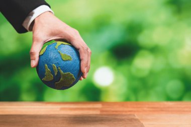 İşadamı temiz enerji ve sıfır CO2 emisyonu kullanarak sürdürülebilir dünya için çevresel farkındalığın sembolü olarak kağıt toprağı elinde tutuyor. Dünya 'yı kurtarmak için yeşil politikası olan çevre dostu bir şirket. Değiştir