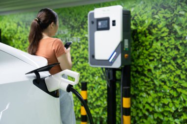 Yeşil kaynaktan karbondioksit salınımını azaltmak için şarj istasyonuna kadar sürdürülebilir enerji ve eko enerji kavramında elektrik şarj istasyonu .
