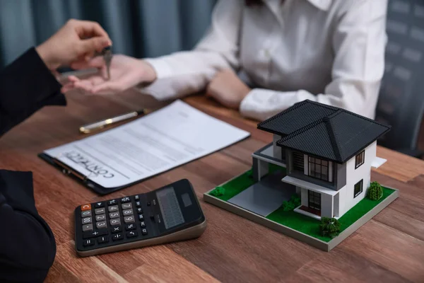 stock image Focus house model on blurred real estate agent hands over the key to the buyer background as a symbol of ownership after the successful completion of the house loan agreement. Enthusiastic