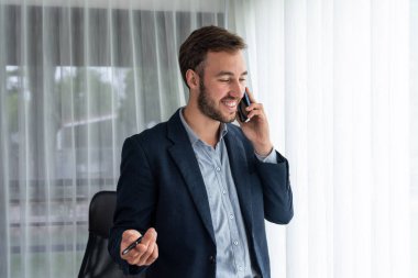 Çalışkan iş adamı, modern ofiste güvenilir bir şekilde müşteriye ikna edici satış çağrıları yapıyor. Ofis çalışanı telefonda konuşuyor ve iş arkadaşlarıyla iş görüşmesi yapıyor. Varlık