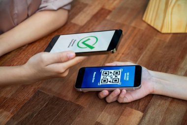 QR kodu parasız ödeme taraması için ekranda gösterilir. Kapalı eller, mobil uygulamadan elektronik işlem yoluyla para aktarmak için akıllı telefonu tutuyor. Hızlı ödeme için barkod teknolojisi. Coşkulu.
