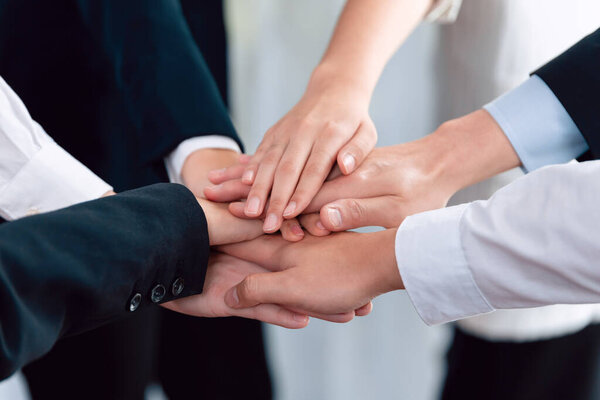 Top view closeup business team of suit-clad businesspeople join hand stack together. Colleague collaborate and work together to promote harmony and teamwork concept in office workplace.