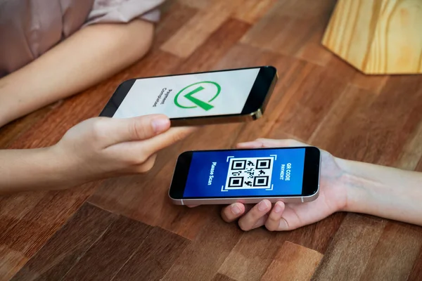 QR kodu parasız ödeme taraması için ekranda gösterilir. Kapalı eller, mobil uygulamadan elektronik işlem yoluyla para aktarmak için akıllı telefonu tutuyor. Hızlı ödeme için barkod teknolojisi. Coşkulu.