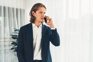 Çalışkan iş adamı, modern ofiste güvenilir bir şekilde müşteriye ikna edici satış çağrıları yapıyor. Ofis çalışanı telefonda konuşuyor ve iş arkadaşlarıyla iş görüşmesi yapıyor. Varlık