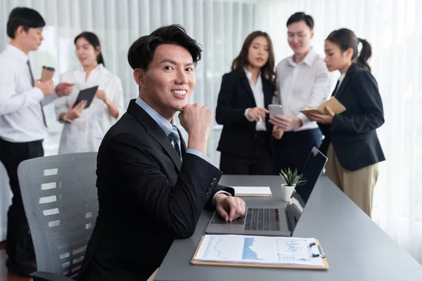 Portrait of focus young successful confident male manager, executive wearing business wear in harmony office arm crossed with blurred meeting background of colleagues, office worker.