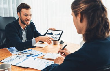 Ofisteki analist ekibi, iş performansını artırmak için tablet ekranında grafik ve grafik olan BI panelini kullanarak çalışma alanındaki pazarlama stratejisi için finansal veri analizi yapmakla meşgul. Varlık