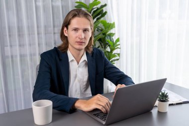 Siyah takım elbiseli bir iş adamı çalışma masasında dizüstü bilgisayarla çalışıyor. Akıllı yönetici finansal verileri araştırıyor ve modern işyerindeki kurumsal dizüstü bilgisayarlarda pazarlama stratejisi planlıyor. Varlık